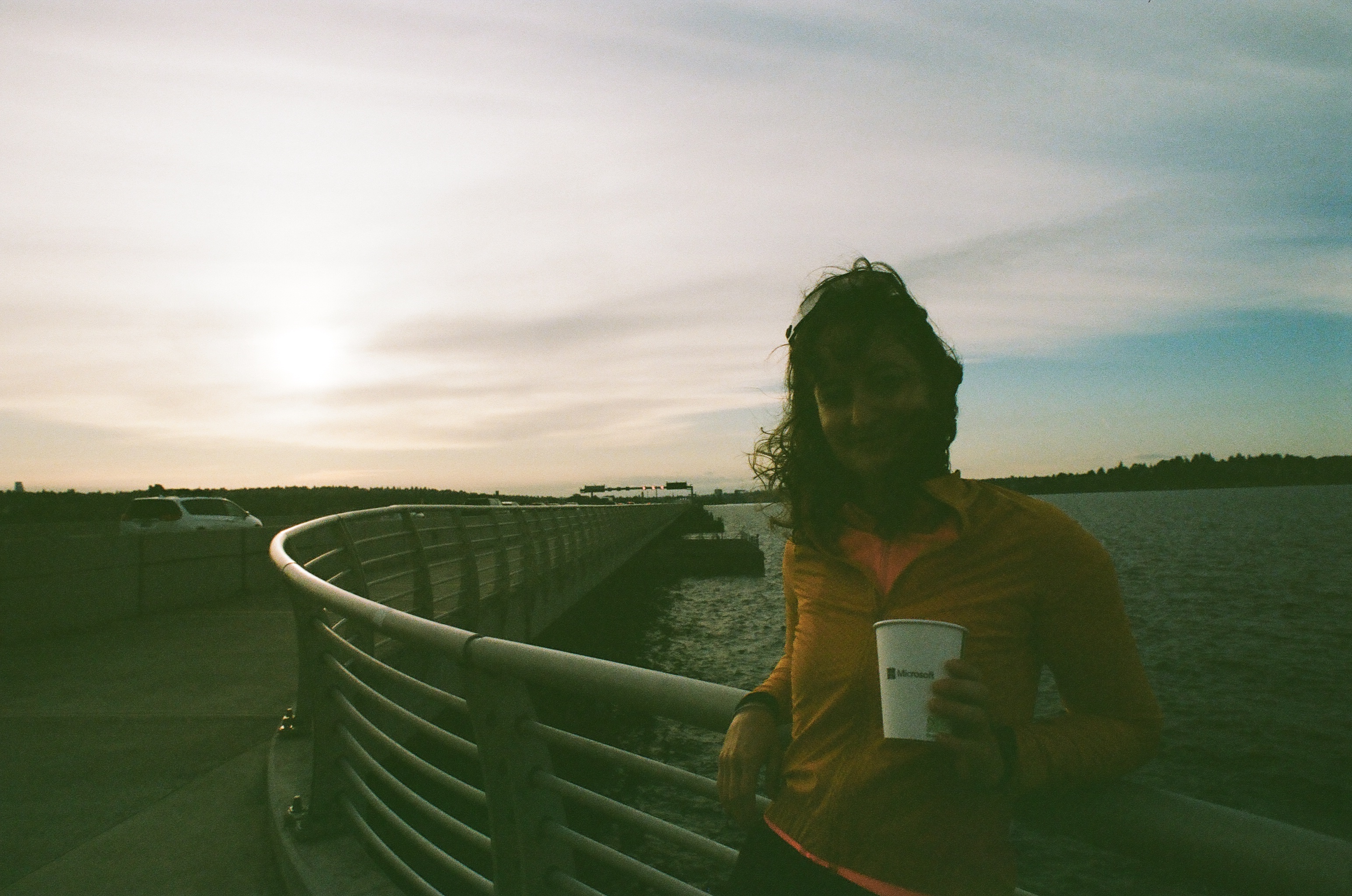 Madeleine on a curving bridge at sunset, holding a Microsoft Research coffee cup